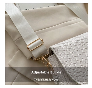 Detail of white woven texture saddle bag with golden metal hardware and wide strap