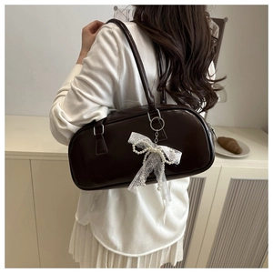 Detail of dark brown leather cylinder bag with lace pearl bow charm and silver hardware