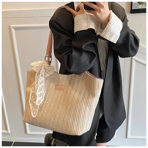 Detailed texture of woven straw tote bag featuring pink leather strap and white lace bow