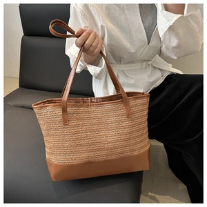 Detail of handwoven straw tote bag with brown faux leather trim and sturdy handles