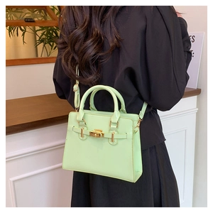 Detail of mint green leather handbag with gold metal lock and adjustable shoulder strap