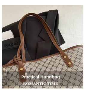 Gros plan d'un cabas vintage à monogramme avec anses en cuir marron et rivets dorés
