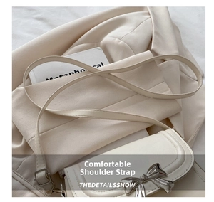 Detail of cream leather crossbody bag featuring a silver metal bow clasp and strap