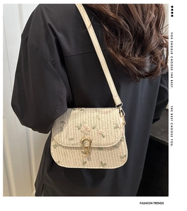 Detailed close-up of cream woven bag with pink flower embroidery and gold metal clasp