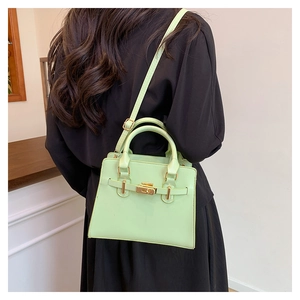 Detail of mint green synthetic leather handbag with gold metal clasp and shoulder strap