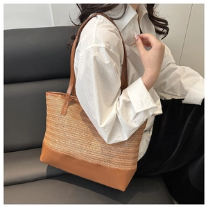 Detail of color-block straw tote bag showing contrast leather trim and woven texture