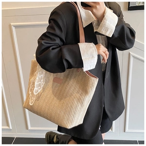 Detail of straw woven tote bag featuring soft pink leather handles and lace scarf accessory