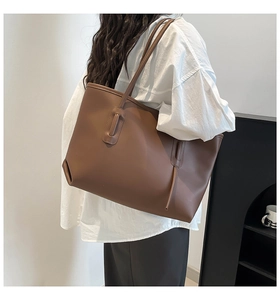 Detail view of large dark brown tote bag with decorative stitching on a model