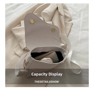 Interior view showing capacity of the beige woven saddle bag with phone and wallet