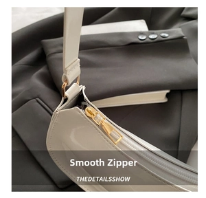 Détail du zip doré et de la texture en cuir verni blanc brillant du sac à bandoulière