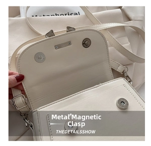 Detailed view of the double magnetic snaps and silver hardware on a cream flap bag