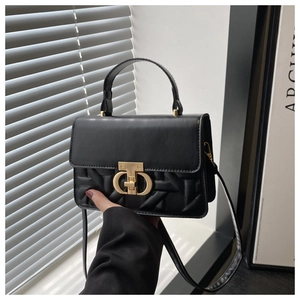 Detail view of black quilted leather handbag with gold metal clasp and woven texture