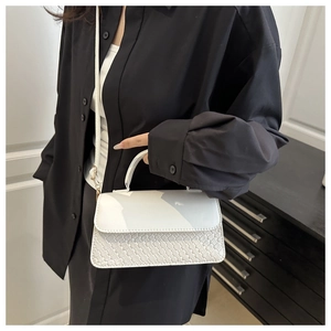 Detail of white minimalist handbag with woven texture and adjustable shoulder strap