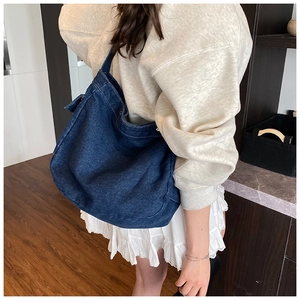 Détail d'un grand sac cabas en denim bleu foncé avec texture délavée et surpiqûres