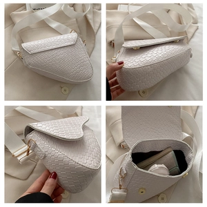 Detail view of woven white saddle bag showing gold hardware and spacious interior