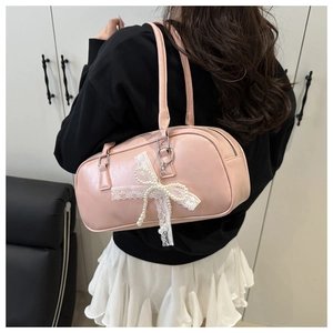 Close-up of pink minimalist handbag featuring lace and pearl bow charm detail