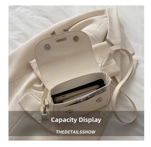 Internal view showing the spacious main compartment and front pocket of the beige crossbody bag