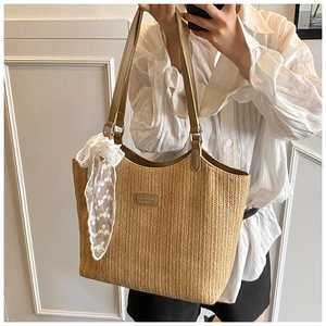 Detail of woven straw tote bag with white lace ribbon and square logo patch