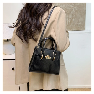 Detail of classic black mini handbag with gold twist lock on beige blazer outfit