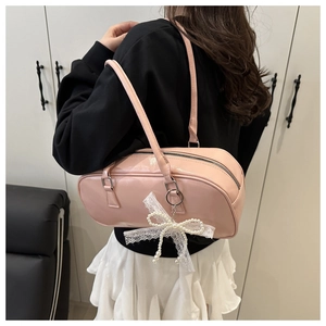 Detailed view of pink glossy Boston bag with pearl lace bow and silver hardware