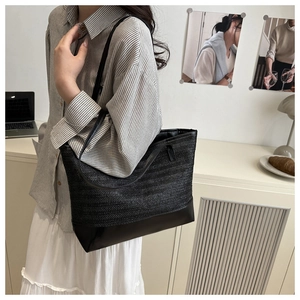 Detail of black woven tote bag featuring leather bottom panel and large capacity design