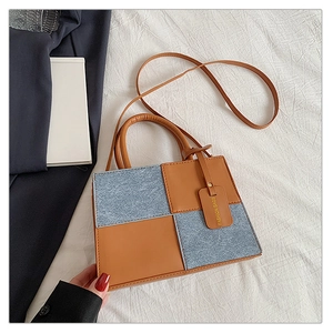 Detail of contrast patchwork small square bag with denim fabric and brown leather straps