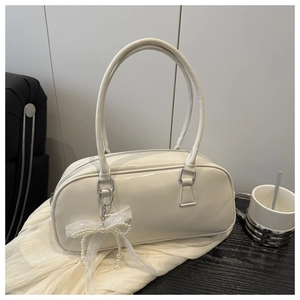 Detail of white patent leather handbag with a delicate lace bow and pearl charm