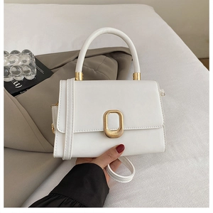 Detail of elegant white crossbody bag with textured gold buckle and minimalist leather finish