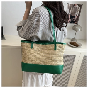 Detail of straw woven tote bag with green leather trim worn on the shoulder in a lifestyle setting