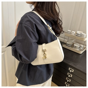 Detail of white leather crescent shoulder bag featuring a gold buckle and elegant silhouette