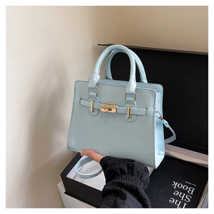 Detail of light blue handbag with gold twist-lock, belt buckle, and leather texture