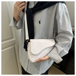 Detail of white woven texture saddle bag with gold metal buckle and wide shoulder strap