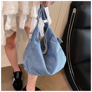 Detail of blue denim hobo bag showing its natural drape and wide shoulder strap texture