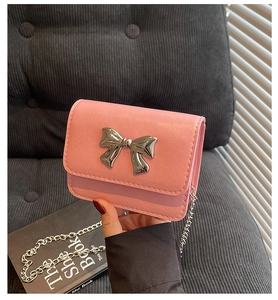Detailed view of pink mini chain bag with silver metal bow and PU leather texture