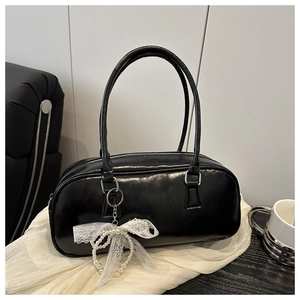 Detail of black leather handbag featuring white lace bow and elegant pearl charm detail