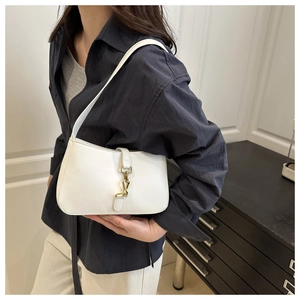 Détail du sac à bandoulière en cuir blanc avec fermoir en métal doré sur veste