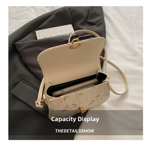 Detail view of woven straw crossbody bag with floral embroidery and golden metal lock
