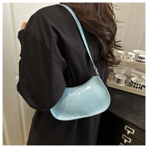 Detail shot of a light blue patent leather shoulder bag worn by a model in a modern home set