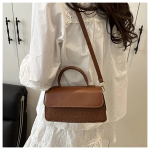 Detail of a brown vintage leather handbag with textured scale pattern and long strap