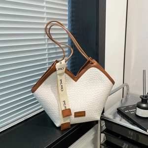 Minimalist woven tote bag with brown leather handles and adjustable shoulder strap