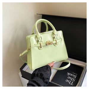 Close-up of mint green leather handbag with gold twist lock and chic belt detail