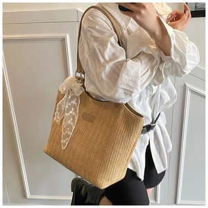 Detailed close-up of handmade straw tote bag with white lace ribbon decoration