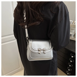 Silver metallic crossbody bag featuring a delicate metal bow clasp and slim shoulder strap