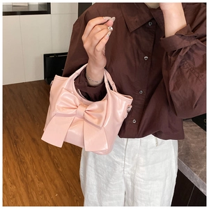 Detailansicht der rosa Beuteltasche mit großer Schleife und glänzender Lederoptik für Damen