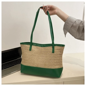 Detail of hand-woven straw tote bag with green leather base and slim shoulder strap