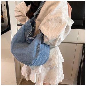 Dettaglio borsa hobo in denim azzurro con tasca laterale indossata da una modella