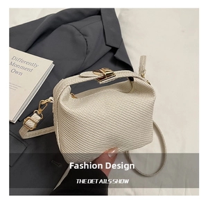 Close-up of cream woven handbag with gold buckle clasp and adjustable strap
