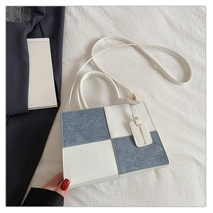 Detail of blue denim and white leather patchwork handbag with checkerboard pattern