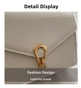 Detailed macro view of cream crocodile-textured leather and gold metal twist-lock buckle