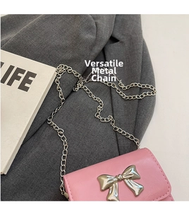 Close-up of pink mini crossbody bag with silver bow detail and metallic chain strap